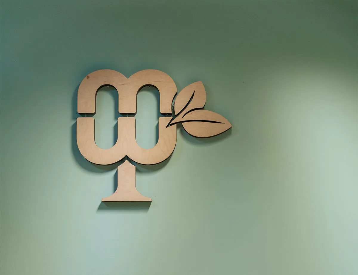 meinwoody Bildmarke aus Holz an pastellgrüner Wand